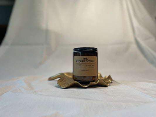 Candle labeled 'The Resurrection' on a decorative brass holder against a white background
